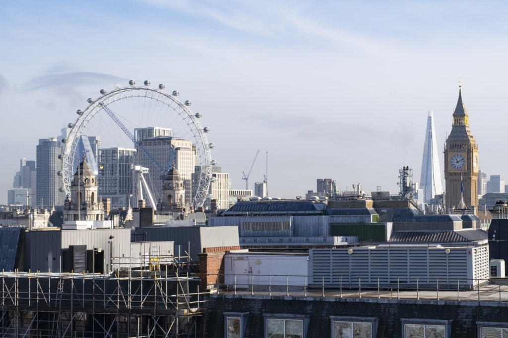 View of London skyline featuring the London Eye, the Shard, Big Ben, and surrounding buildings with bespoke commercial rooflights under a clear sky.