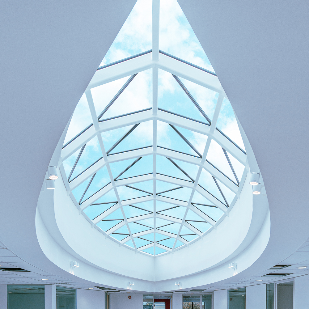 A large skylight with a geometric pattern, letting in natural light, is set in a white ceiling, creating a bright and open atmosphere.