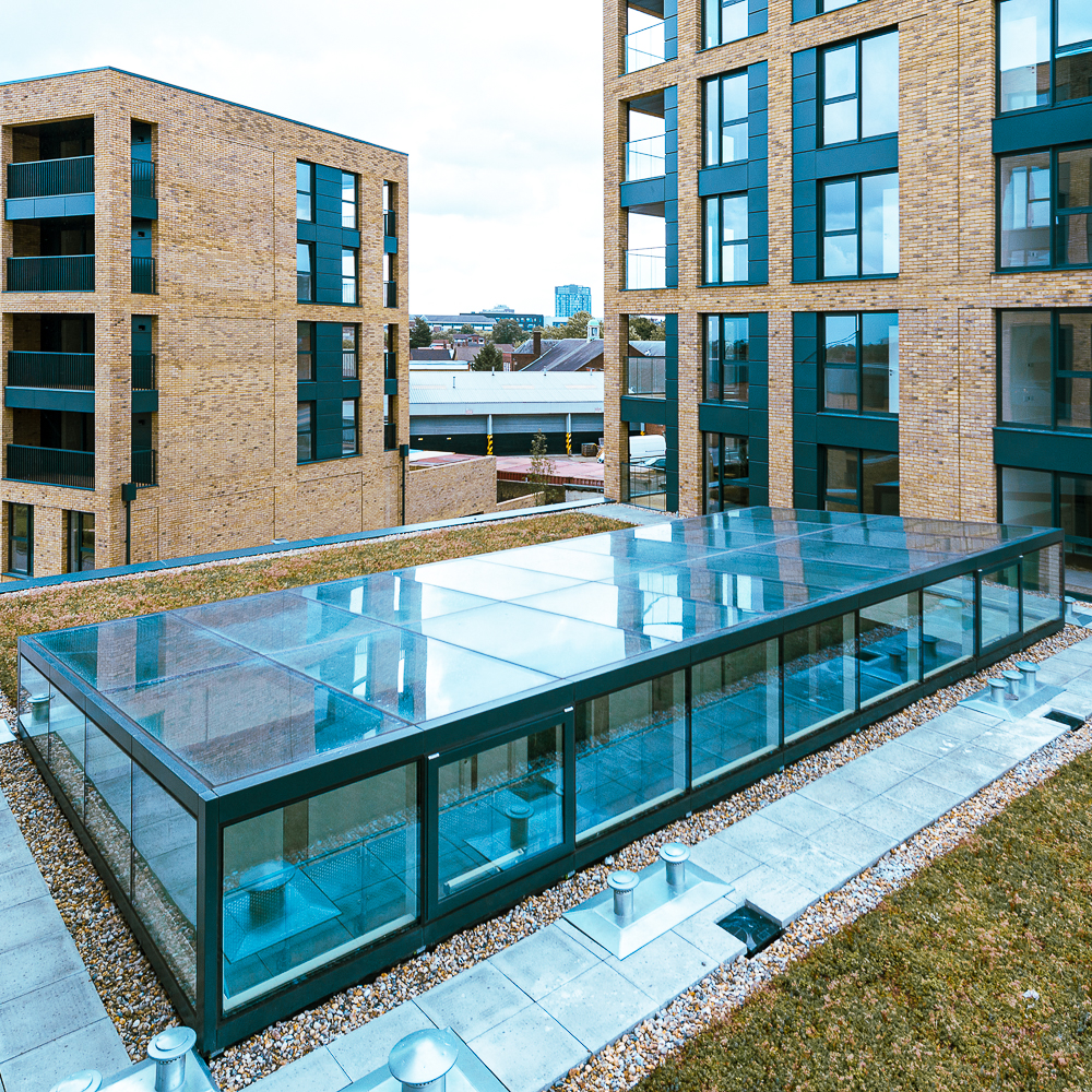 Rooftop view of modern brick apartment buildings featuring a large glass structure with surrounding green space and pathways.