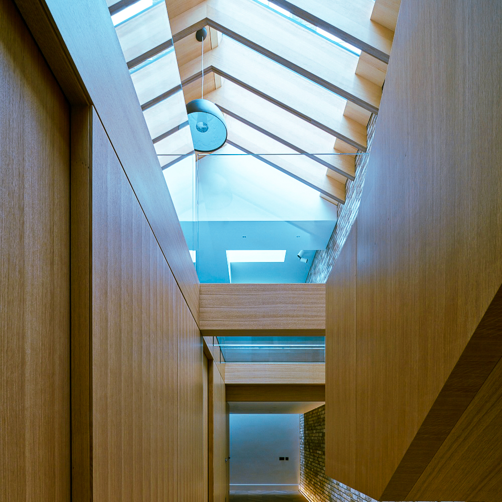 Interior view of a modern hallway with wooden walls and a glass ceiling, allowing natural light to illuminate the space.