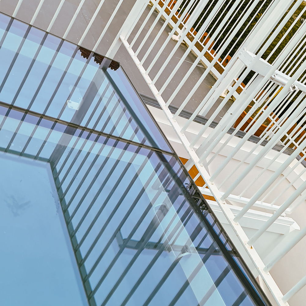 A glass table reflecting the sky and surrounding white railing bars.