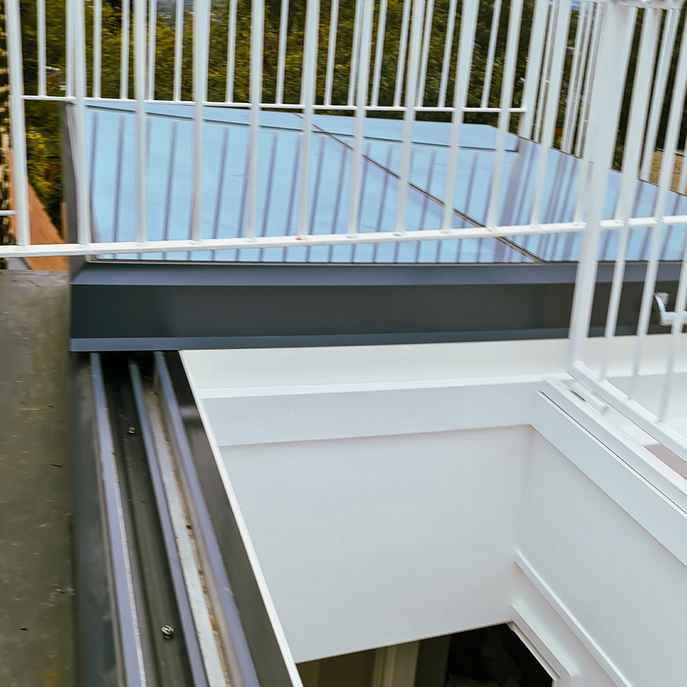 View of a building rooftop with glass panels and white metal railings.