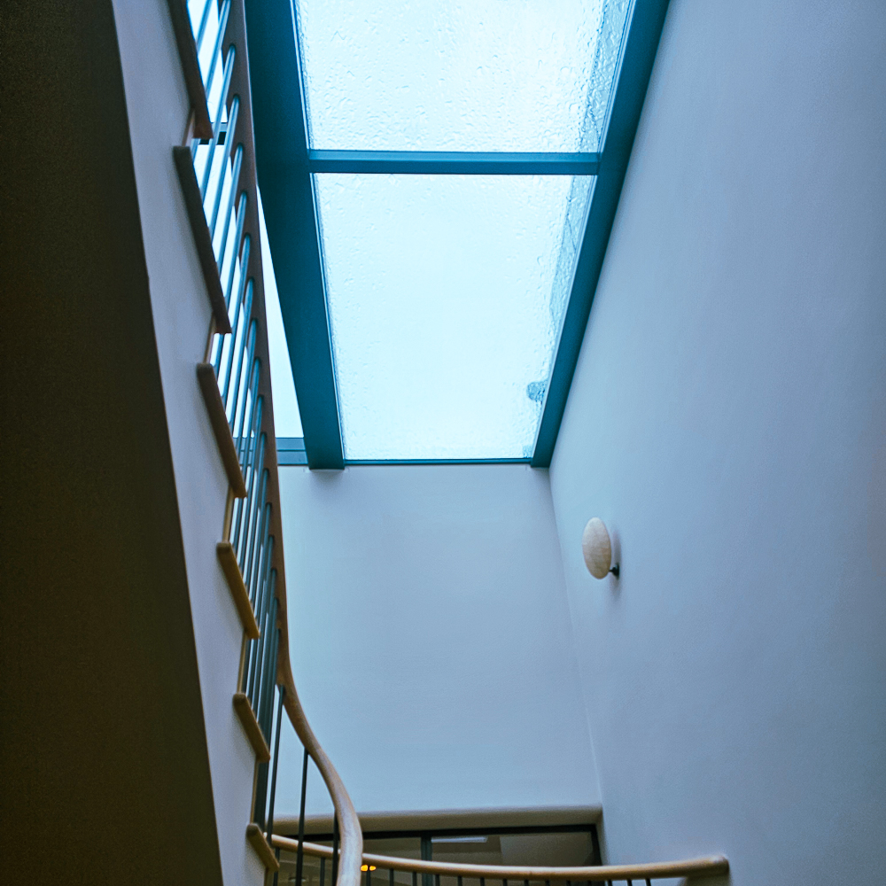 A staircase with metallic railings leading to a skylight ceiling.