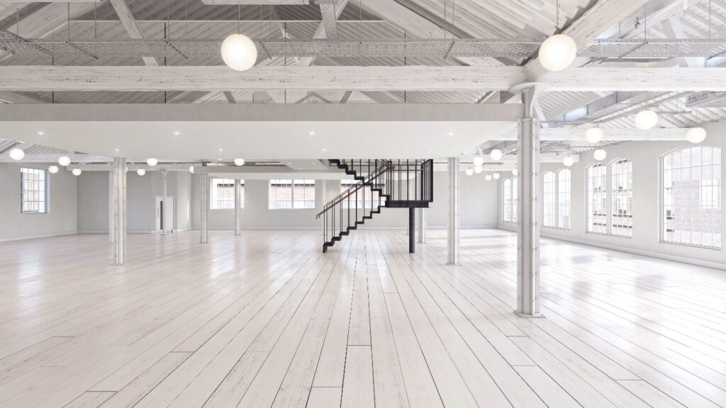 Spacious, modern loft with white wooden floors, large windows, exposed beams, columns, globe lights, bespoke glass boxes, and a central black spiral staircase.