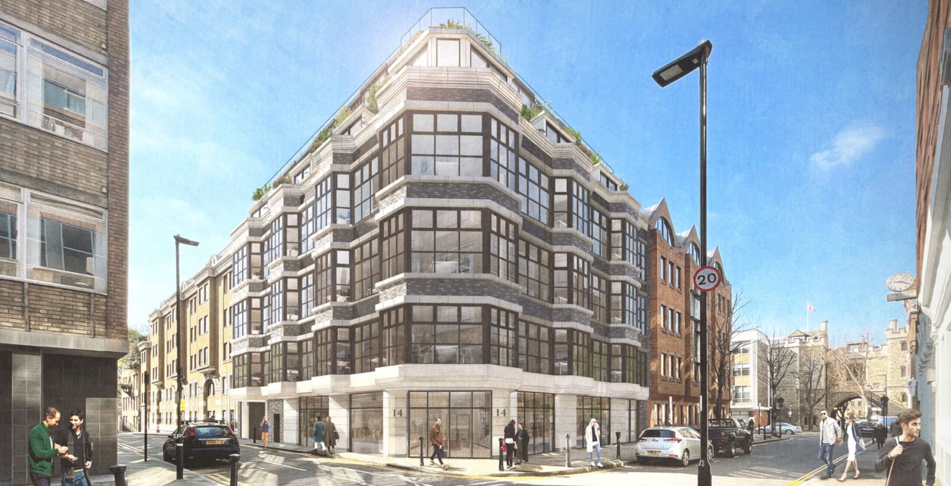 Street view of a modern multi-storey building with large windows and brick located at a corner junction with pedestrians and cars under a clear blue sky.